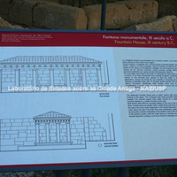 Painel de sítio com reconstituição e explicação sobre a fonte monumental do século III a.C.