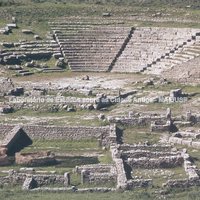 Vista do teatro com suas estruturas de cena. Em primeiro plano o santuário das divindades crônicas na ágora.