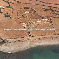 Tenos. Vista aérea do complexo do Santuário de Poseidon e Anfitrite, com indicação de ruínas e do caminho pavimentado até o mar. 